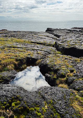 Rock pool on the lava reflecting the sky