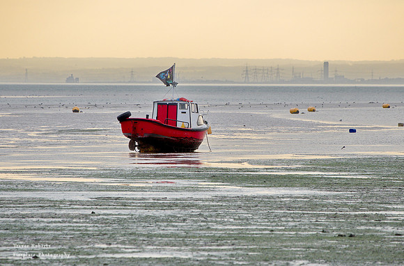 Shoeburyness  East beach. Red boat on the mud  under an orange sky
